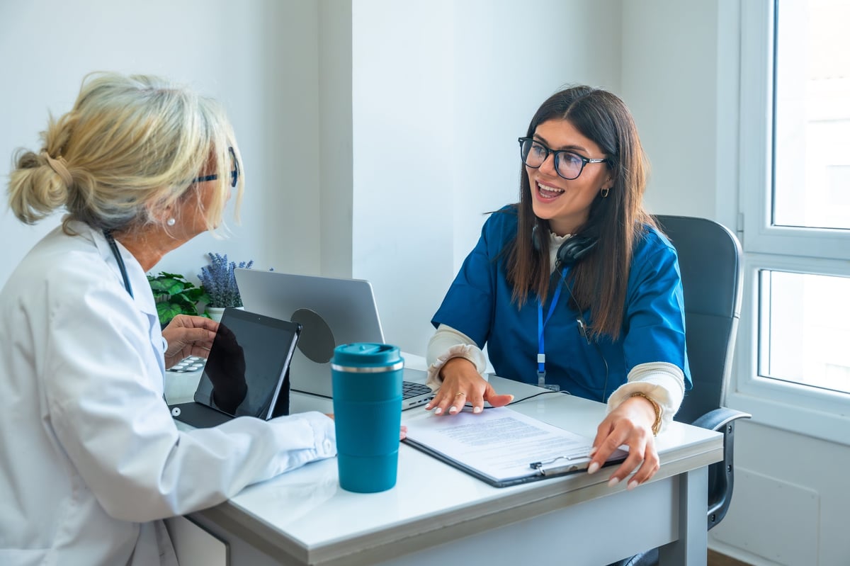 Two clinicians reviewing patient records together in a hospital office